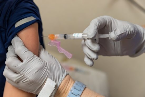 Nurse giving vaccine shot in arm of child, medical concept